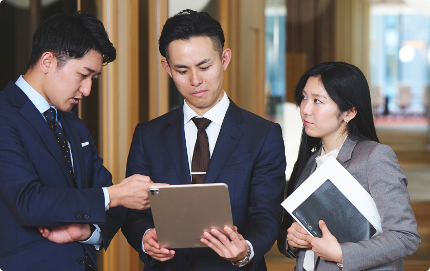 複数の社員がパソコンに向かって意見を出し合っている様子